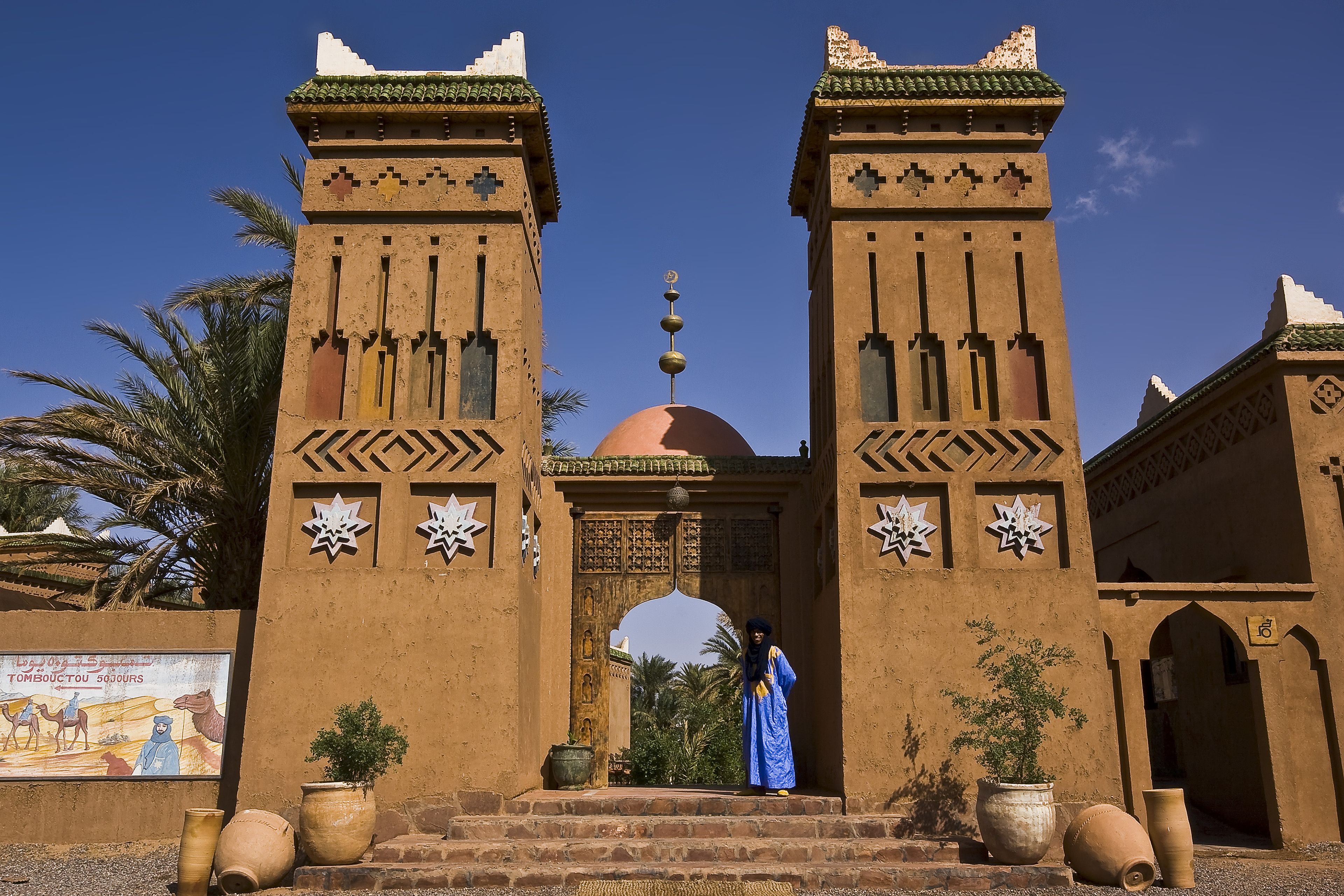 A traditional Moroccan gate with geometric patterns and a clear blue sky.