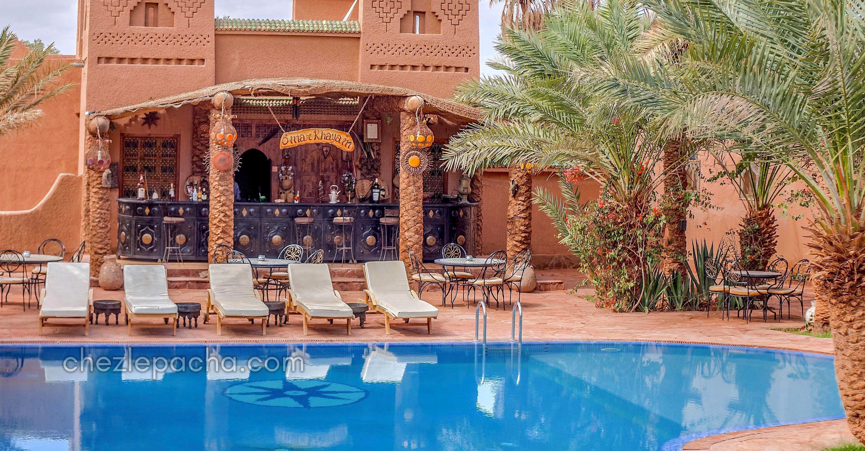 A pool area with lounge chairs and a bar area with a sign reading "Sma' Khayel".