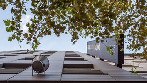 A modern building with a large metallic sculpture in the foreground and a sign with Korean text in the background. - Porto Trindade Hotel (Porto)