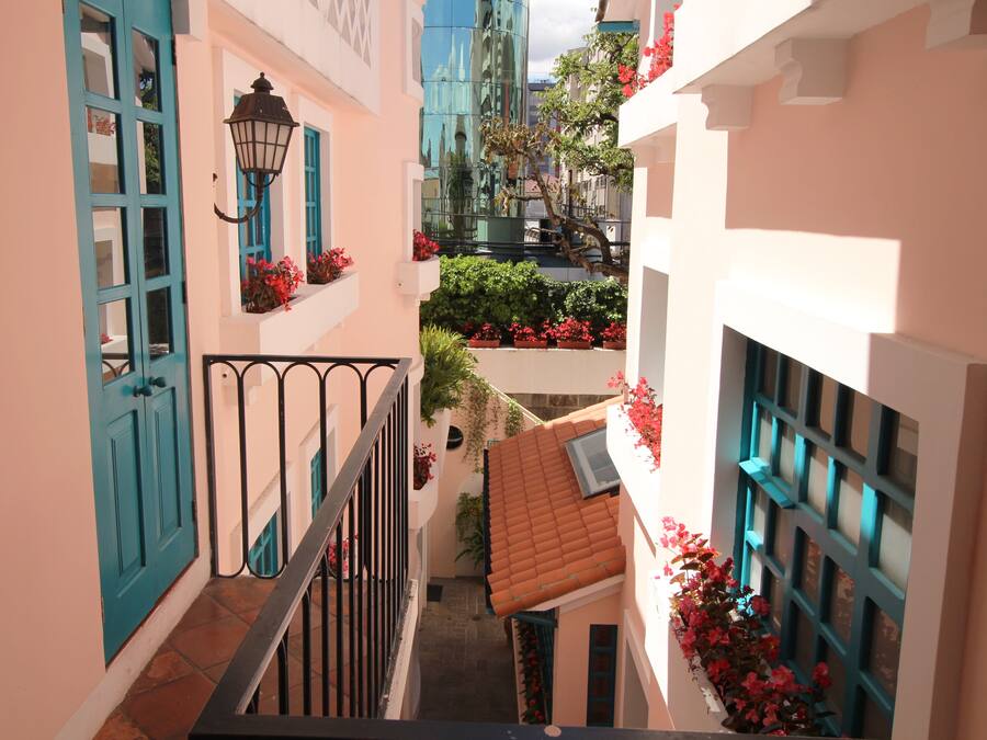 Um beco estreito com uma escadaria, uma porta azul e um candeeiro.