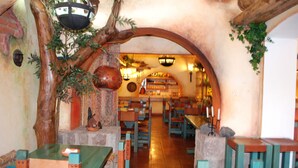 A restaurant with rustic decor, including wooden tables and chairs, a brick wall, and a hanging light fixture. - Vieja Cuba Hotel (Quito)