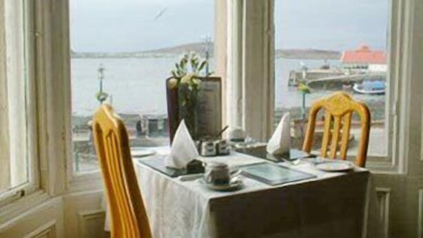 Une table à manger recouverte d’une nappe blanche, un vase rempli de fleurs et une chaise sur laquelle est posée une serviette jaune.