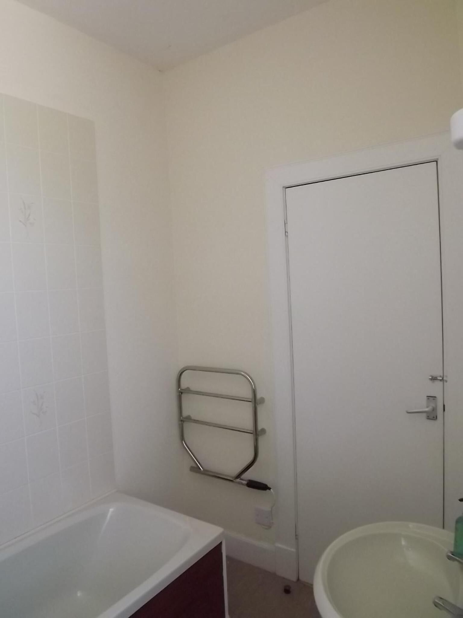 Une salle de bain avec une baignoire, un lavabo et une porte.