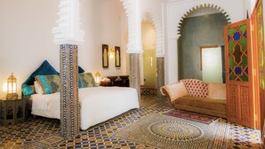A room with a bed, a sofa, a patterned floor, and a decorative door.