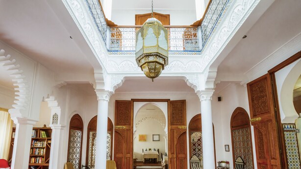 An interior with arches, a chandelier, and a dining area.
