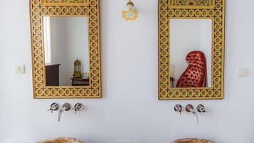 Two ornate mirrors with geometric patterns, a wooden vanity table, and two ceramic bowls.
