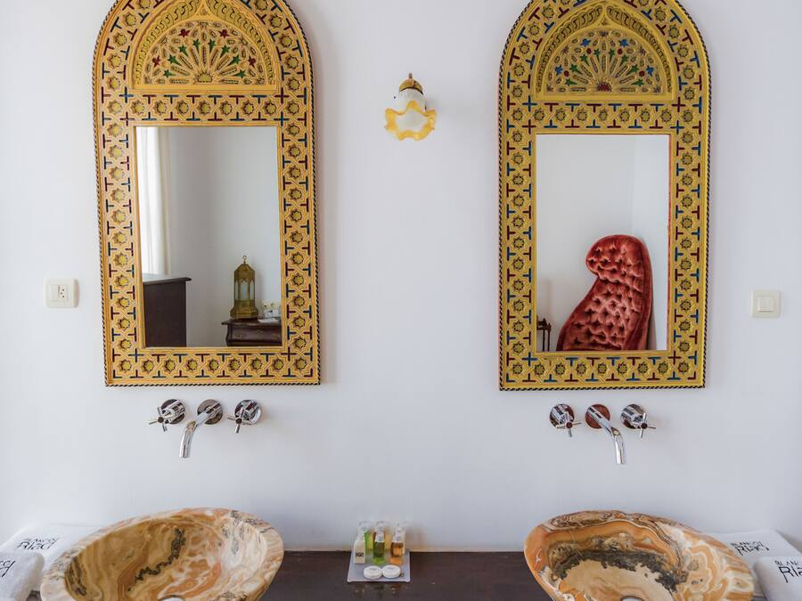 Two ornate mirrors with geometric patterns, a wooden vanity table, and two ceramic bowls.