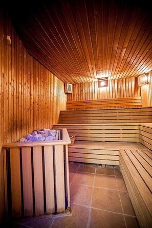 A sauna with wooden benches and a central heated stone feature.