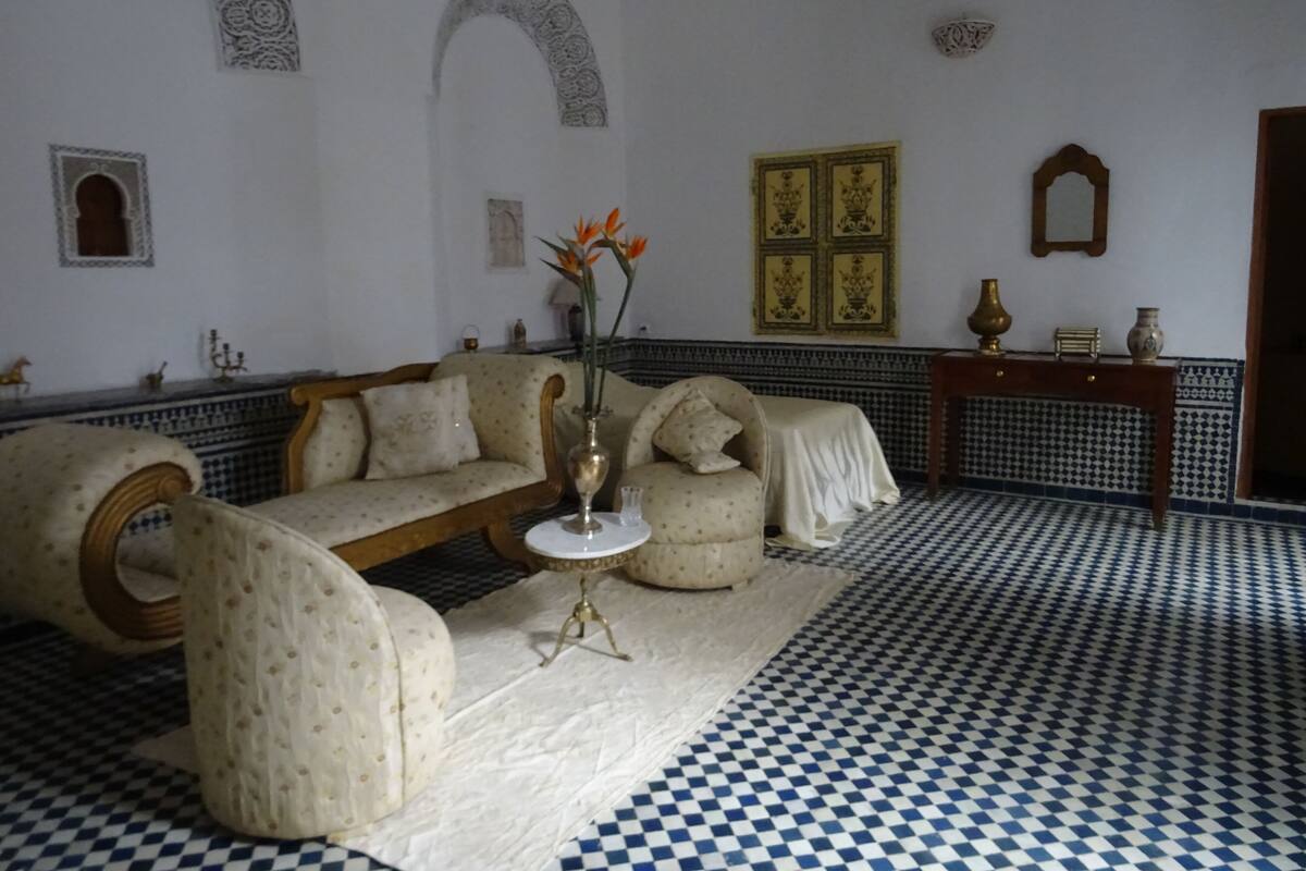 A room with a checkered floor, a sofa, a small table with a vase, and decorative wall panels.