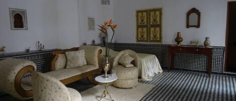 Una habitación con suelo a cuadros, un sofá, una mesita con un jarrón y paneles decorativos en la pared.