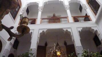 Interior con varios niveles, arcos ornamentados y un candelabro central.