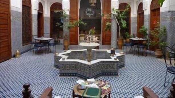 Un patio con una fuente, suelo de baldosas y zonas de estar.
