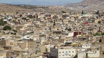 A densely packed urban area with numerous buildings, some with satellite dishes, and a mountainous backdrop.