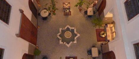 A courtyard with a central fountain, seating areas, and potted plants.
