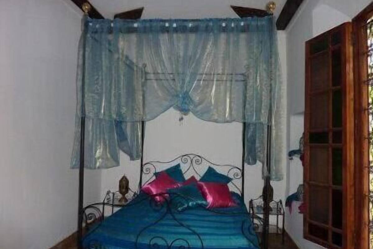 A bed with a canopy, a wooden window, and a metal headboard.