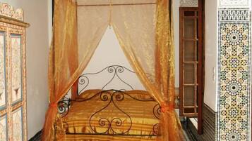 Una habitación con una cama bajo un dosel, un armario de madera y paredes con diseño.