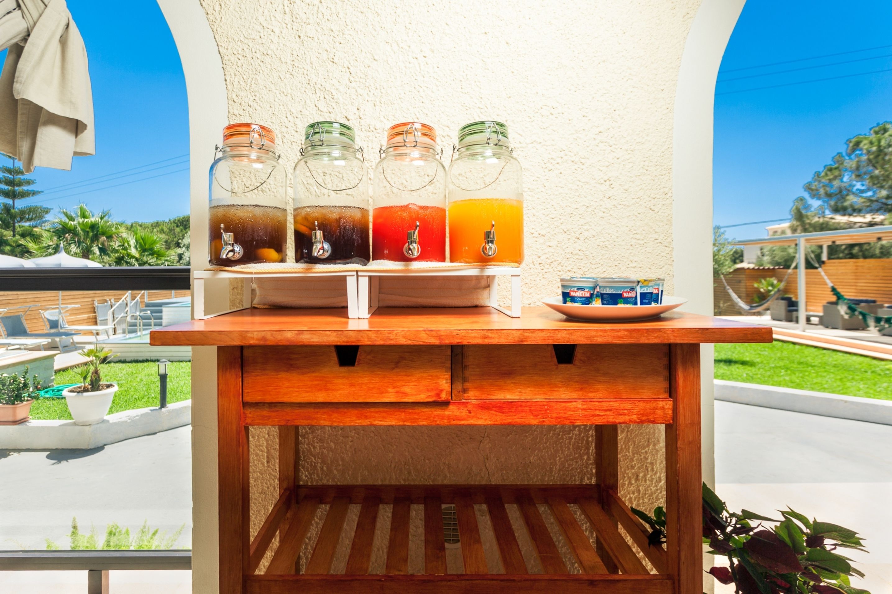 A beverage station with four glass dispensers, each containing a different drink, and a bowl of snacks.