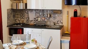 Cocina compacta con comedor, televisor y refrigerador rojo.