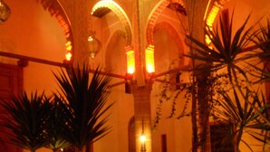 An indoor courtyard with arches, palm trees, and a fountain. - Riad Kalaa (Rabat)