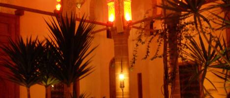 Un patio interior con arcos, palmeras y una fuente.