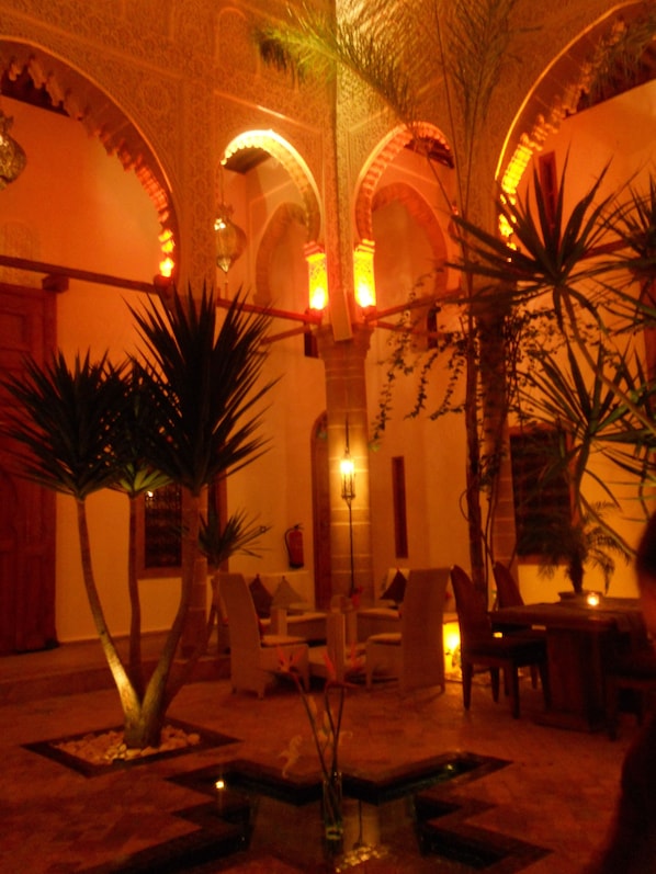 An indoor courtyard with arches, palm trees, and a fountain.