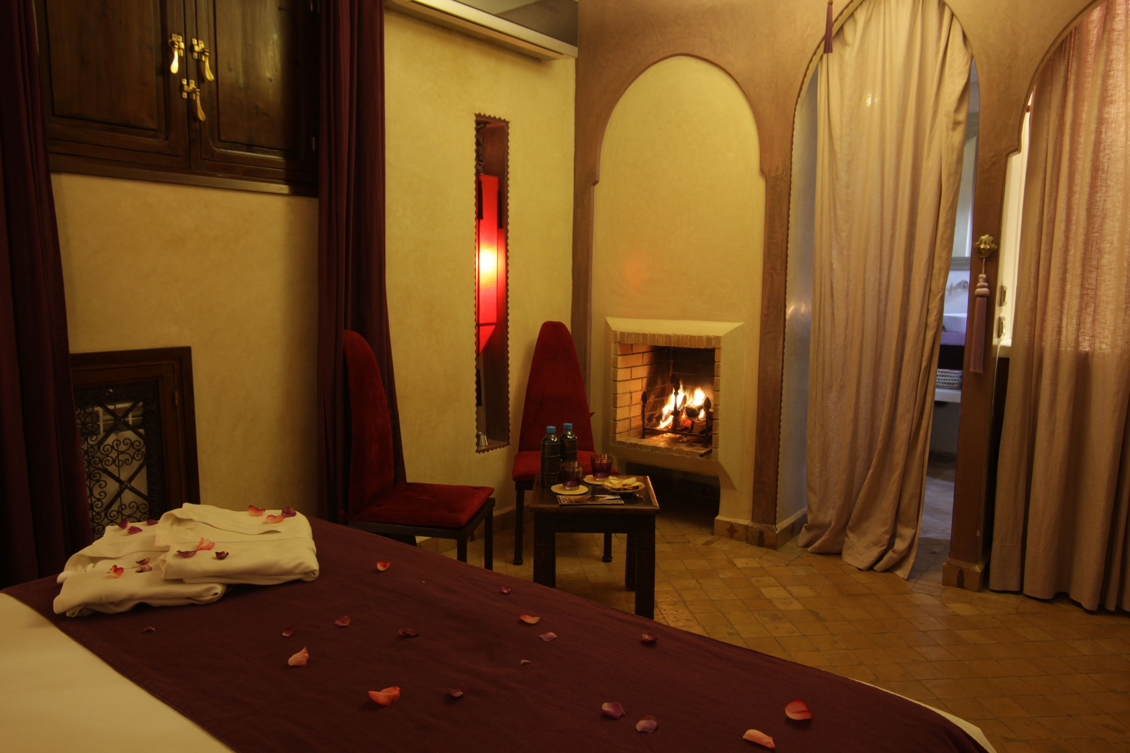 Una habitación con una cama, una chimenea, una mesa con una bandeja y una silla.