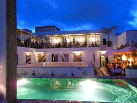 Una piscina al aire libre, sombrillas, sillones reclinables de piscina