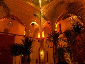 An interior with arches, a chandelier, and potted plants.