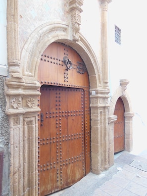 Una puerta de madera grande con remaches metálicos, ubicada en un arco de piedra.