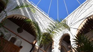An ornate architectural structure with intricate designs and arches, featuring a clear blue sky above. - Riad Kalaa (Rabat)