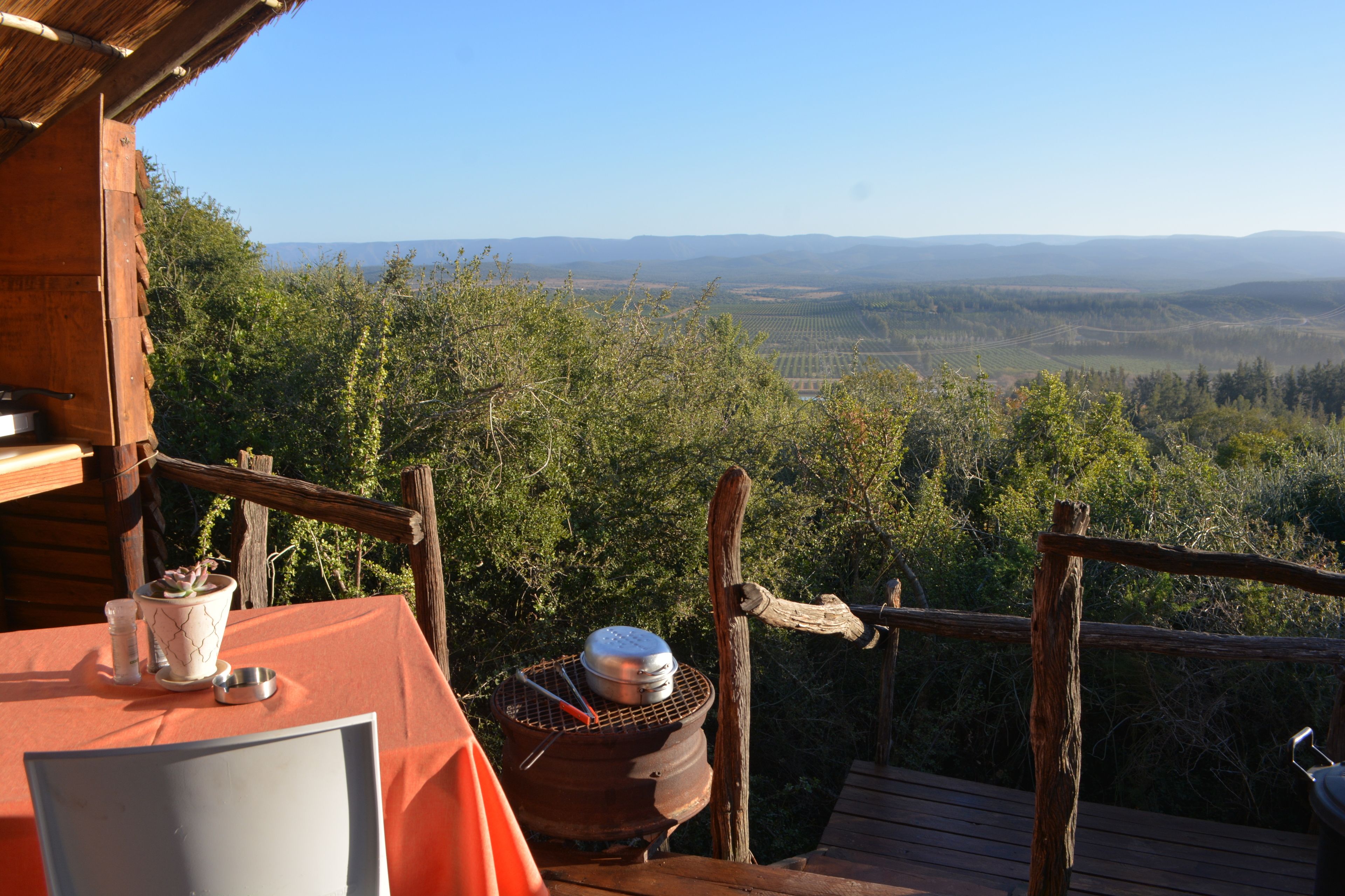 A wooden deck with a table, a pot, and a grill.