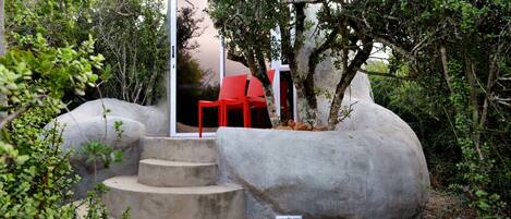 A concrete structure with steps leading to a red chair, surrounded by greenery.