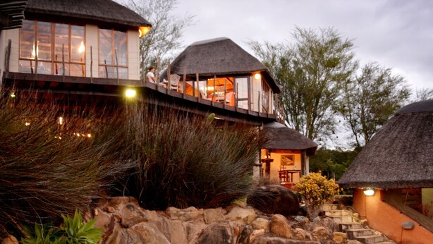 A resort with a pool, thatched-roof structures, and a stone pathway. - Addo Dung Beetle Guest Farm (Addo)