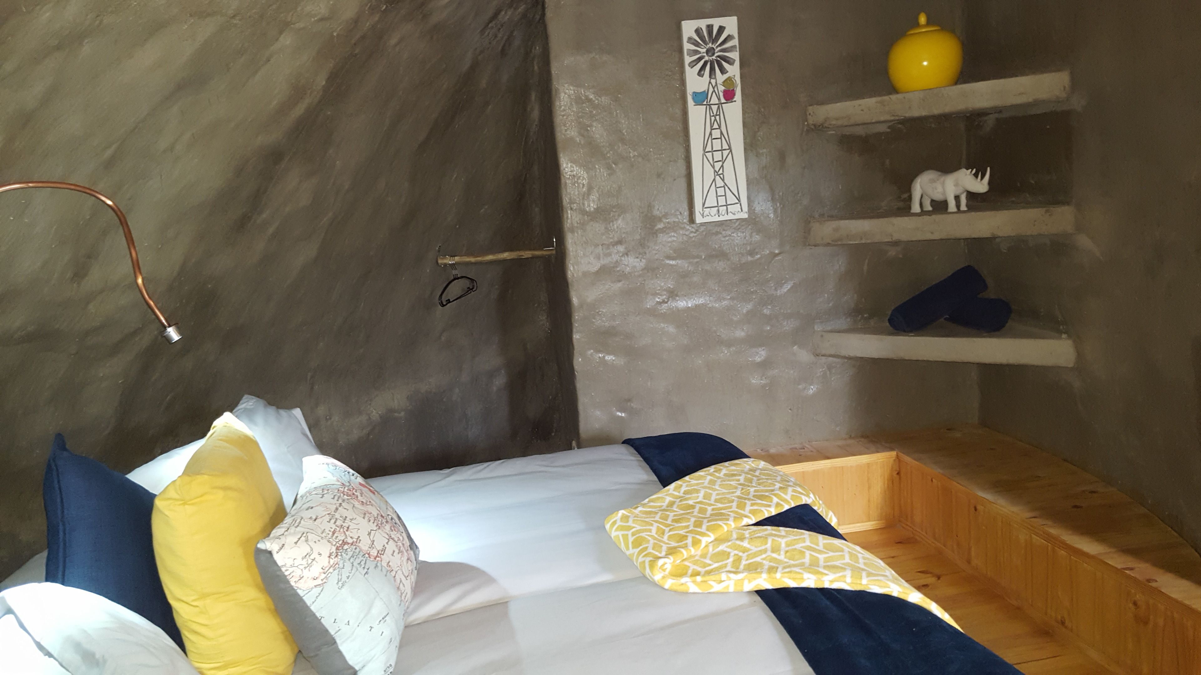 Um quarto aconchegante com uma cama, um travesseiro em formato de mapa, um globo e uma estante com objetos decorativos.