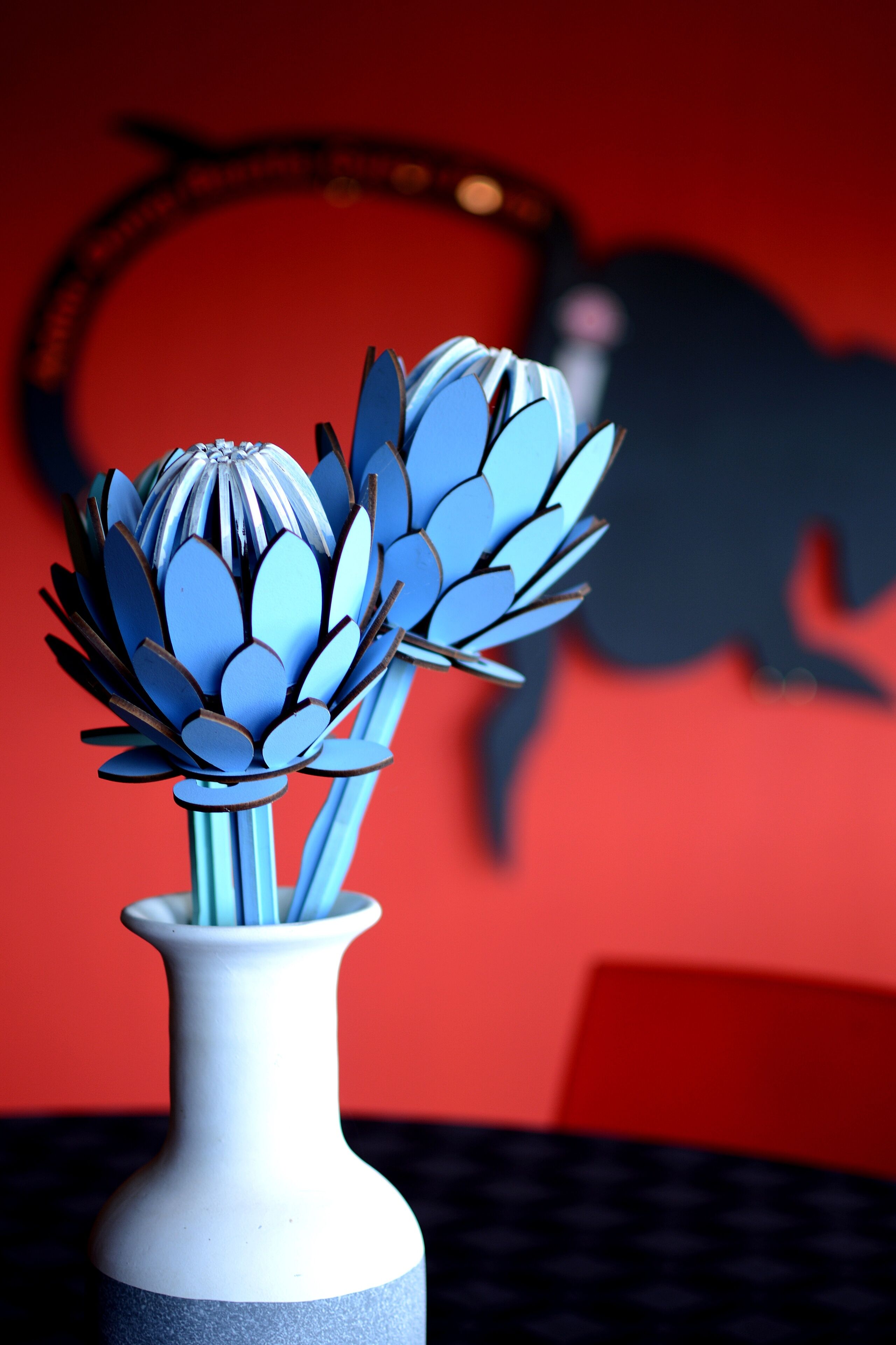 A white vase with a blue base on a table.