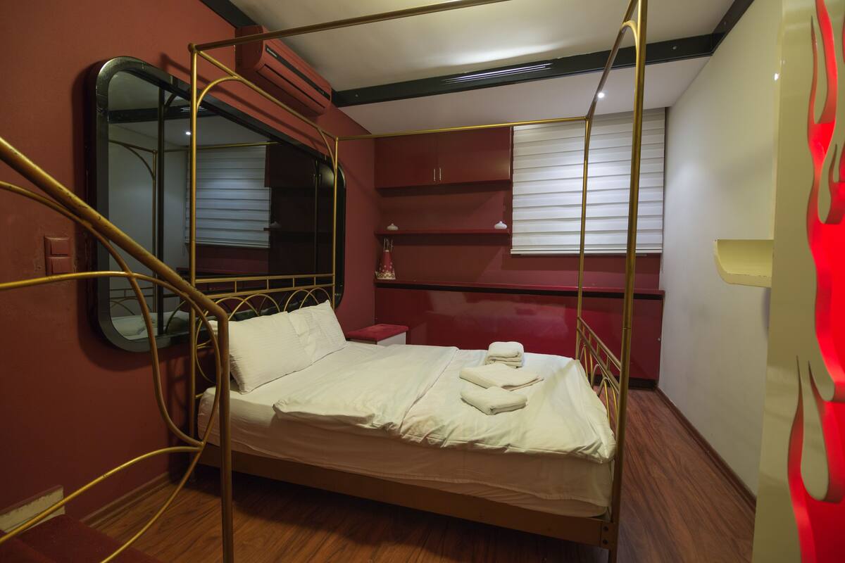 A four-poster bed with a wooden frame, a small bedside table, and a mirror.