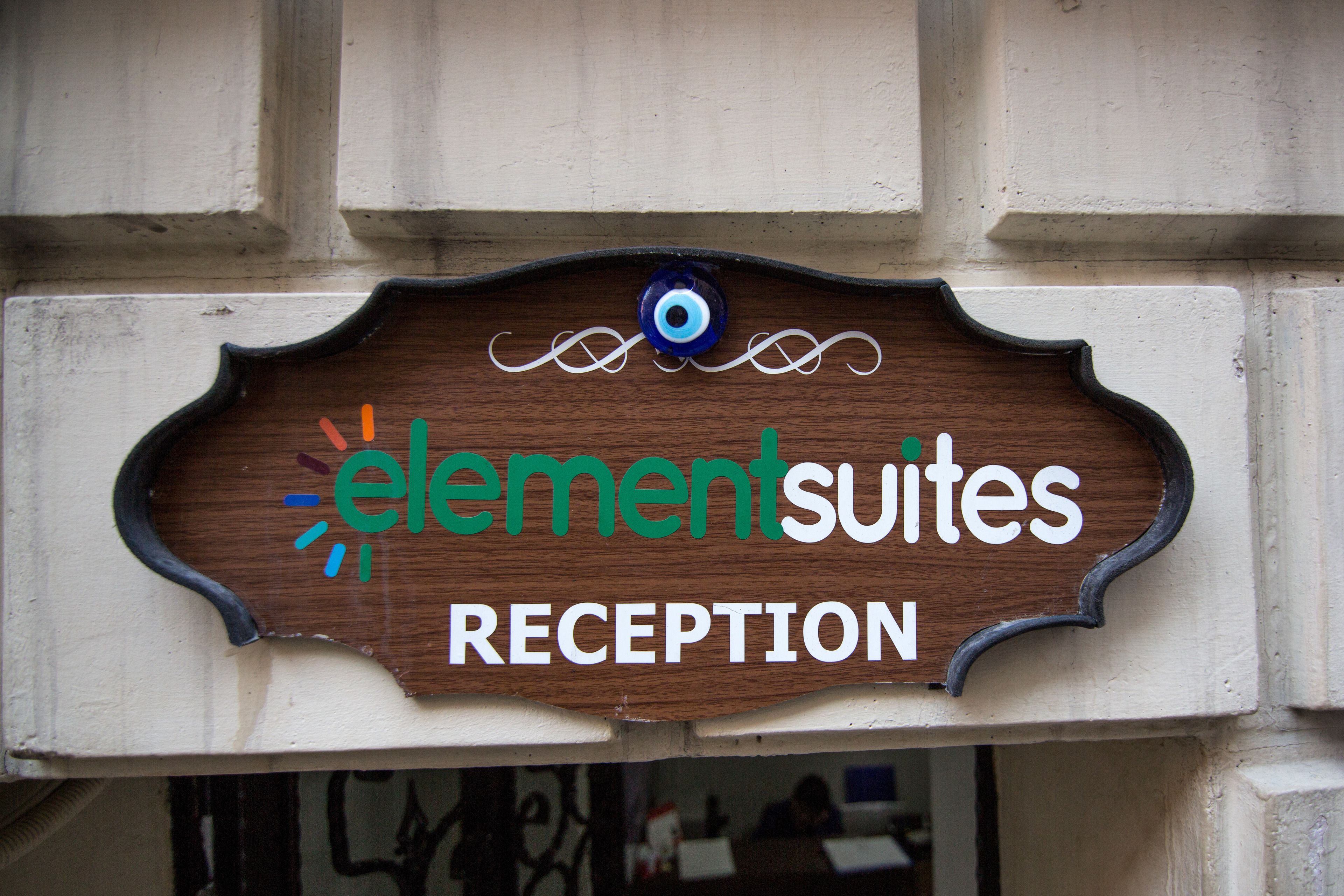 A wooden sign with the text "elementsuites RECEPTION" mounted on a building facade.