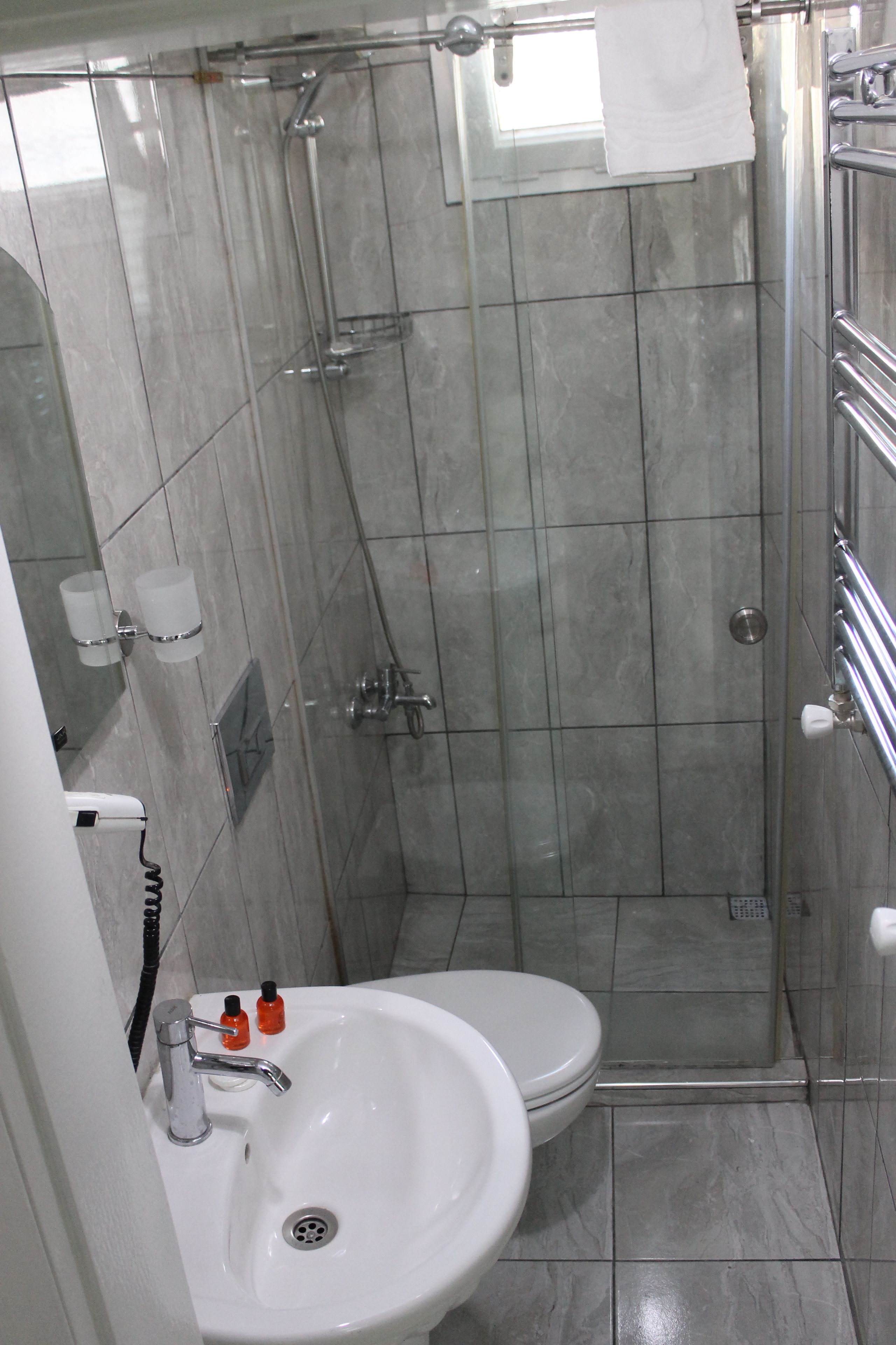 A bathroom with a white sink, toilet, and glass-enclosed shower stall.