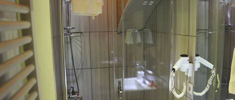 A modern bathroom with a glass shower enclosure, a visible towel rack, and a sink with toiletries.