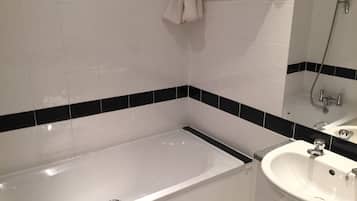 A bathroom with a bathtub, a sink, and a mirror.