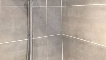 A shower with a handheld showerhead and a wall-mounted rain showerhead in a tiled bathroom.
