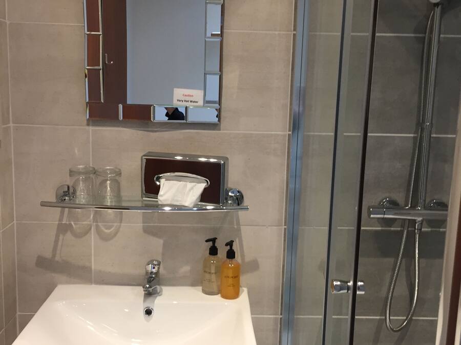 A bathroom with a white sink, a mirror, and a glass shower enclosure.