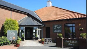 A brick building with a tiled roof, a reception area, and outdoor seating. - Purdy Lodge (Belford)