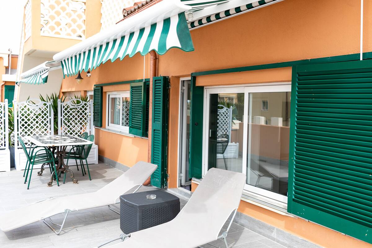 Une terrasse avec une table et des chaises, une petite table ronde et un fauteuil de relaxation.