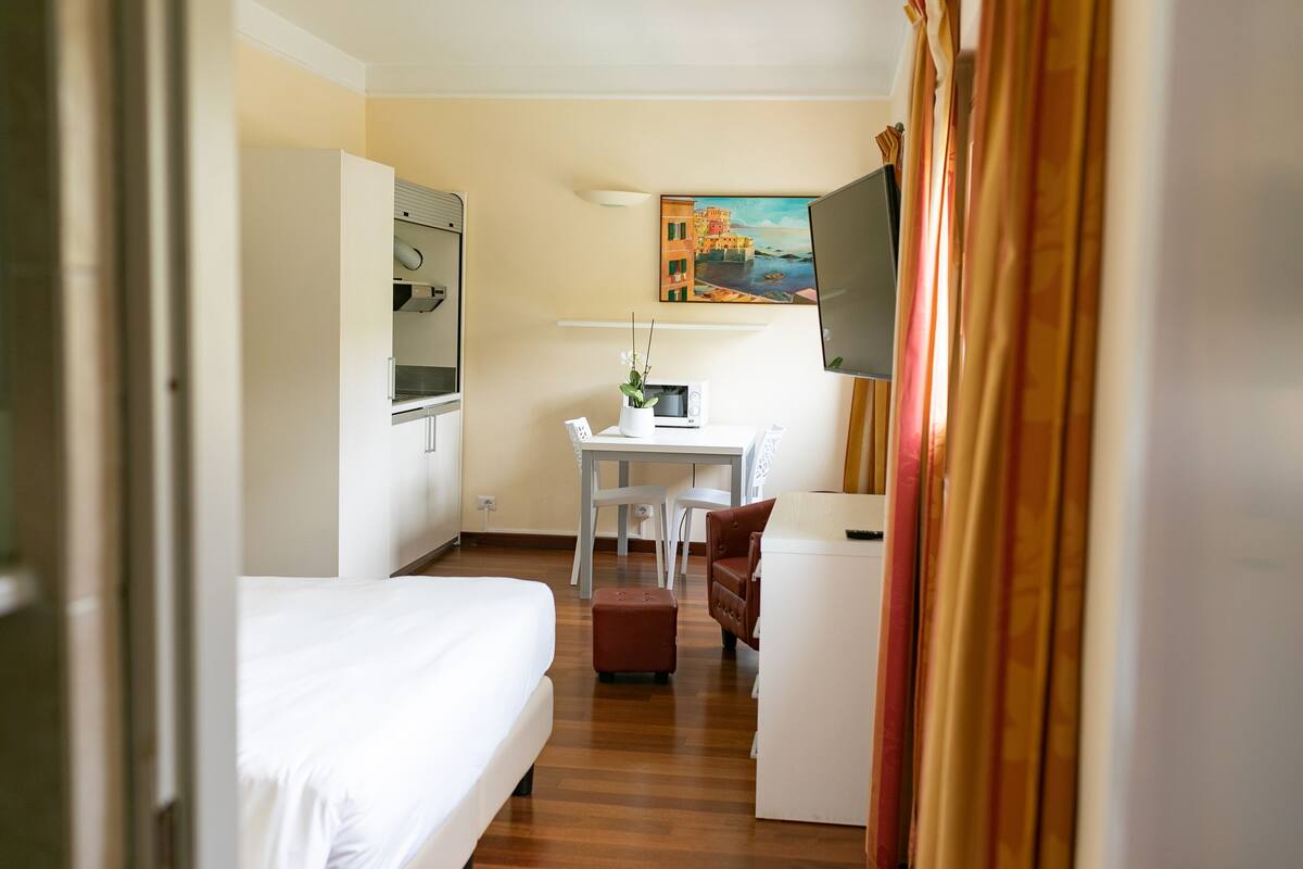 Une chambre d’hôtel avec un lit, un bureau avec un ordinateur, une télévision et un tableau au mur.