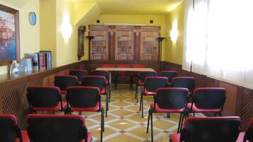 Una biblioteca con filas de sillas rojas y negras, estanterías de madera y un suelo a cuadros.