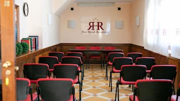 A conference room with a checkered floor, red and black chairs, a table, and a wall with a logo and name.