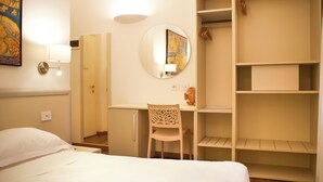 A hotel room with a bed, a desk, a chair, a wardrobe, and a mirror. - Rex Hotel Residence (Genoa)