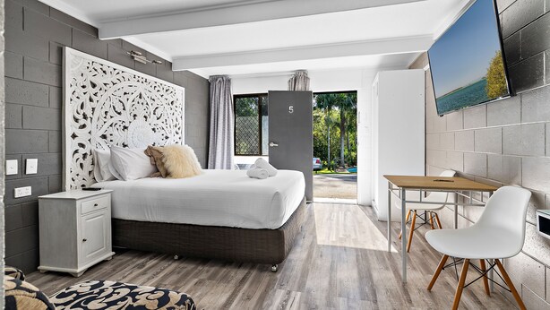 Ein modernes Schlafzimmer mit einem großen Bett, einem Schreibtisch und einem Fernseher.