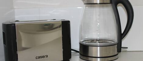 Una cocina con un tostador y una cafetera de vidrio sobre la encimera.